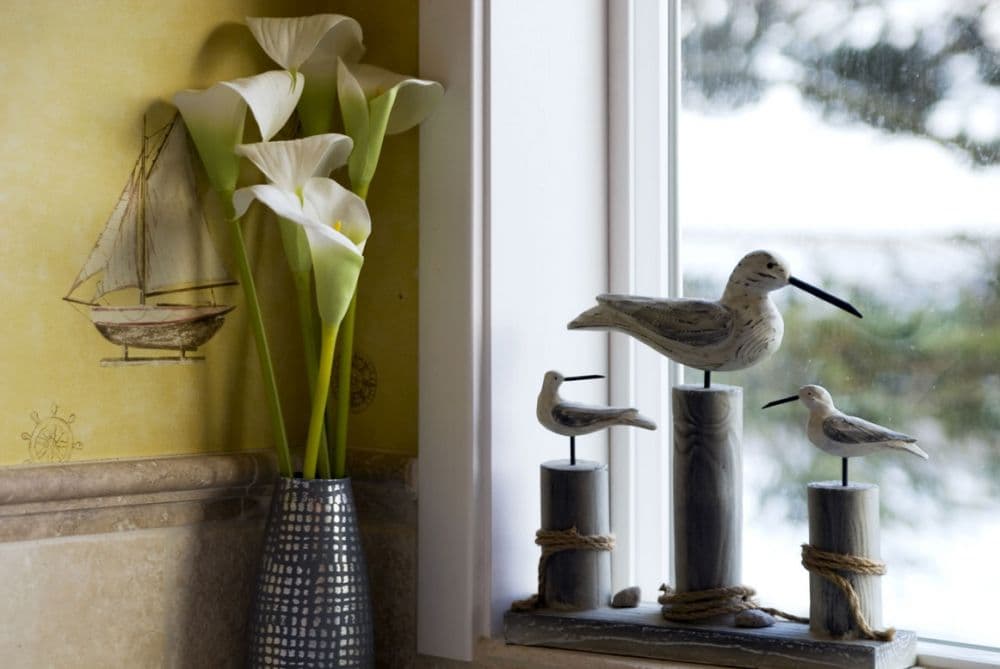 Bright window with natural light, bird figurines, and a vase of lilies, creating a serene atmosphere.